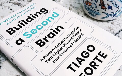 Het boek Building a Second Brain van Tiago Forte op een marmeren tafel
